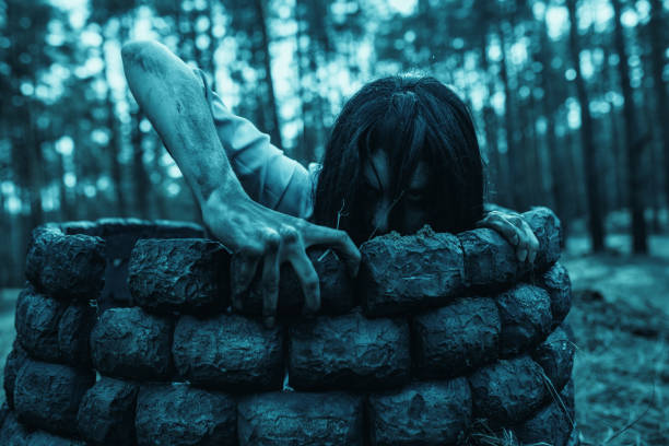 girl in image of scary zombie crawls out of the stone well in dark forest. - vengeful imagens e fotografias de stock
