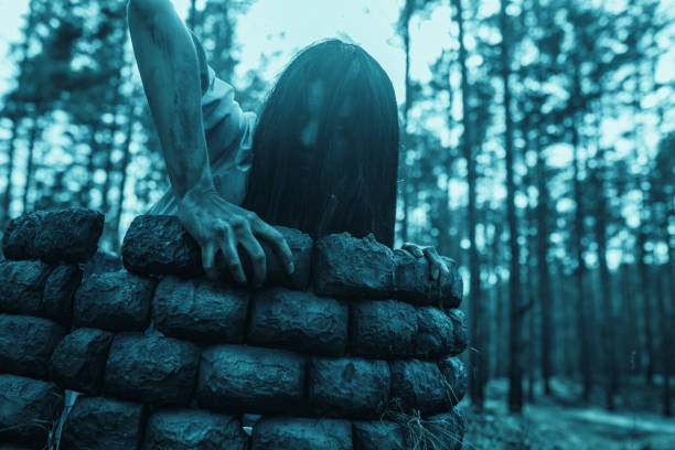 girl in image of scary zombie crawls out of the stone well in dark forest. - vengeful imagens e fotografias de stock