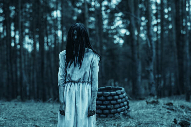 ragazza nell'immagine di zombie spaventosi cammina nella foresta oscura vicino al pozzo di pietra. - vengeful foto e immagini stock
