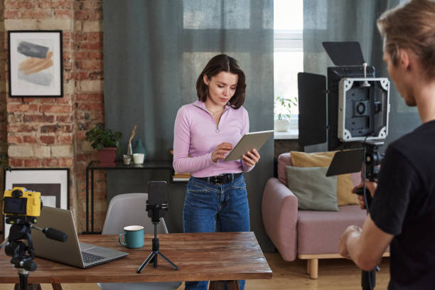 istock Young female expert reading text on tablet while preparing for shoot in living room 1334512748