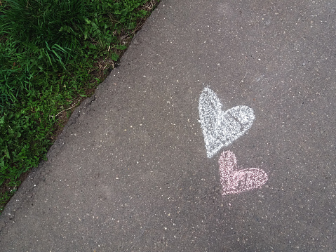 Hearts drawn with chalk on the asphalt sidewalk