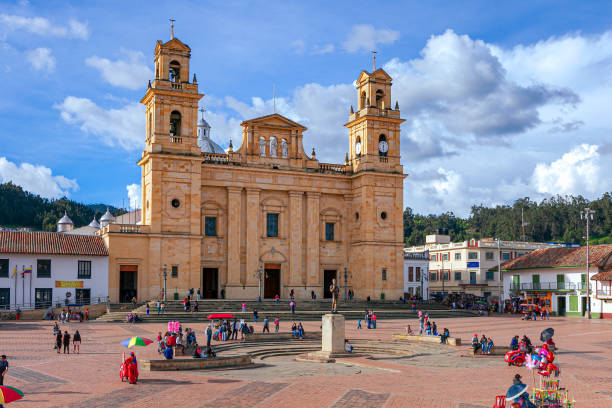 Chiquinquirá, Boyacá Department, Colombia - Local Colombians On The Main Town Square On A Sunday Afternoon; Background: Basilica Of Our Lady Of The Rosary Chiquinquirá, Colombia - November 26, 2017: It is Sunday afternoon on the Plaza Mayor in the Andes town of Chiquinquirá in the Department of Boyacá, in the South American Country of Colombia. Many local residents and Colombian tourists are seen enjoying the ambience of the town square. Vendors sell toys and snacks to visitors. In the background is the 19th Century Basilica of Our Lady of the Rosary. It houses the famous painting of Our Lady of The Rosary, also referred to as the Virgin of Chiquinquirá, the Patron Saint of Colombia. It is designed in the Neo-classical style of architecture and is a destination of Catholic pilgrimage in South America. The altitude at street level is about 8400 feet above mean sea level. Photo shot in the late afternoon sunlight; horizontal format. boyacá department photos stock pictures, royalty-free photos & images