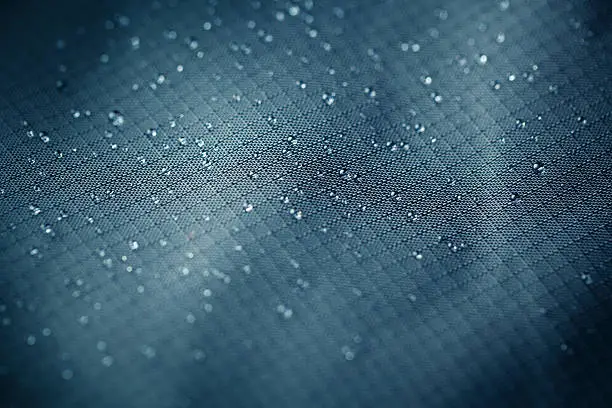 Water droplets closeup on waterproof clothing material.
