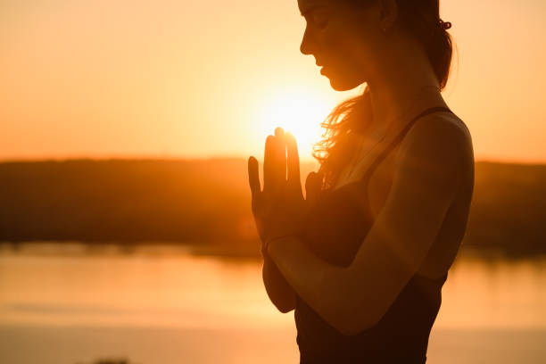Sunny portrait of woman in warm backlit Woman portrait raise hands and face close up in warm sun light outdoor, yoga meditation practice meditation hands stock pictures, royalty-free photos & images