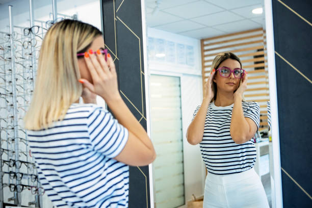 istock Woman trying on glasses in optical store looking at mirror 1334529507