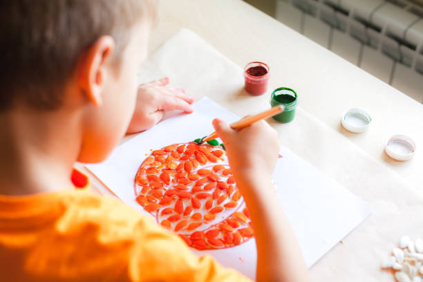istock Making pumpkin from seeds on white paper, Halloween DIY concept 1334530015