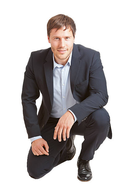 Young business man Successful young business man smiling into camera isolated on white background kneeling stock pictures, royalty-free photos & images