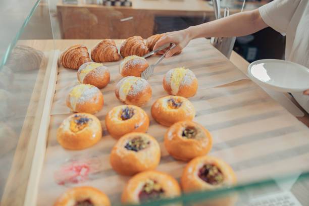 istock Female hand taking bun from display showcase in bakery shop 1334532773