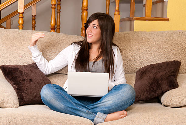 Young woman with laptop portable computer sitting on sofa stock photo