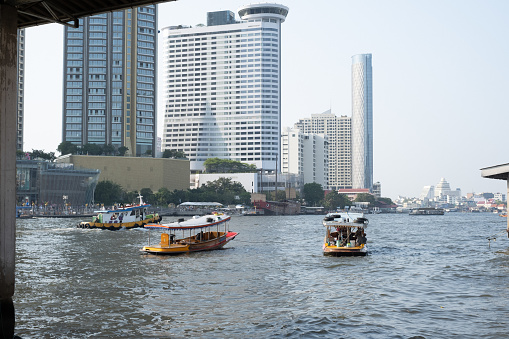 A typical sight in Bangkok: the river, boats and skyscrapers in the background