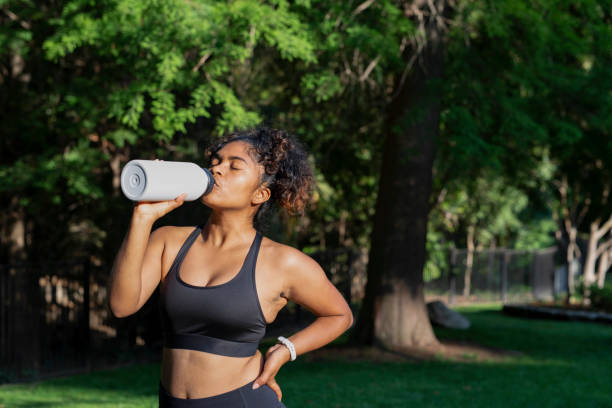 istock woman drinking from water bottle in the park 1334534655