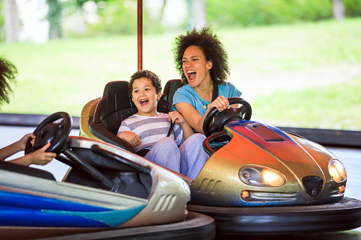 A Cute Little Schoolboy is Excited During the Drive in a Bumper Cars with his Happy Mother and Sister. Cheerful African Woman is Enjoying the Time with her Lovely Kids in Entertainment Park.