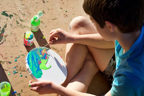 istock Boy Making a Marbled Effect Painting on Round Canvas 1334538677