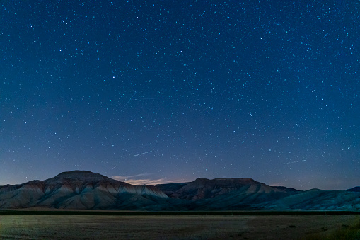 A Mesmerizing Night Landscape under the Bright Milky Way, snow-capped mountains are seen in the distance