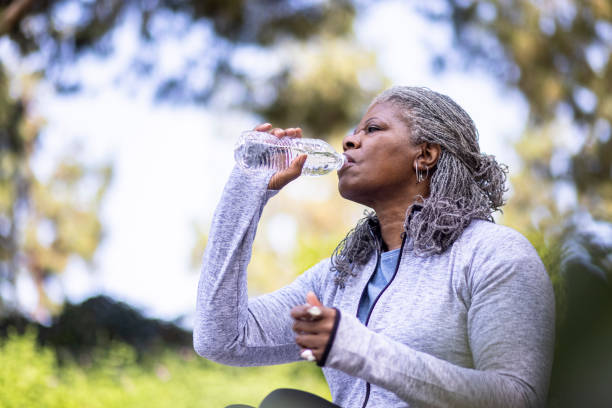 Senior black woman drinking water during workout stock photo