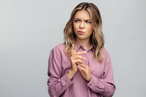 mujer joven confundida mira a un lado con la emoción dudosa y sospechosa pensativo flexión de los dedos - sneering grimacing women human face fotografías e imágenes de stock