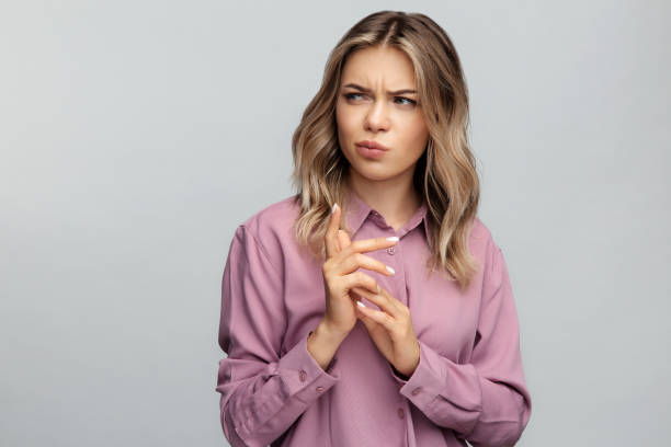 Confused young woman look aside with doubtful and suspicious emotion thoughtful bending fingers Confused young woman looking aside with skeptical and suspicious emotion thoughtful and pensive bending fingers while making decision. Portrait of sarcastic doubtful female isolated at studio wall sneering stock pictures, royalty-free photos & images