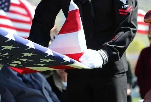 Veteran's Cemetery 2019 - Sailor in dress uniform folding American flag at memorial service, Veteran's Memorial Cemetery, Bluffdale, Utah.