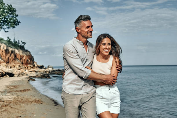 atractiva pareja abrazada en la playa. - bien parecido fotografías e imágenes de stock