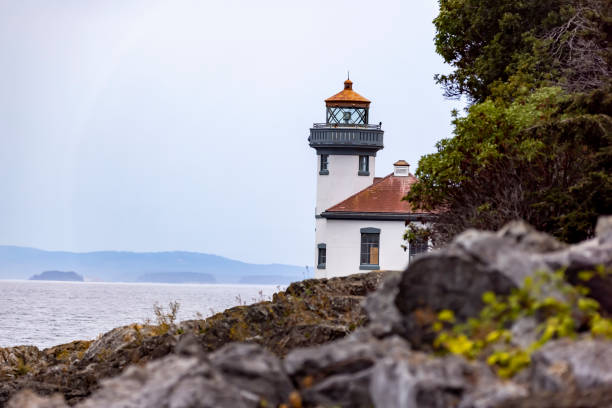 vue du majestueux phare du parc d’état de lime kiln au milieu des arbres et des rochers le long du bord de l’eau - washington state coastline beach waters edge photos et images de collection