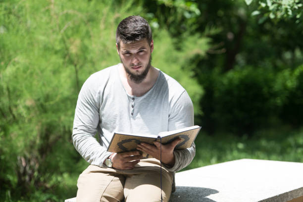 istock Young Muslim Guy Reading The Koran In Park 1334550530