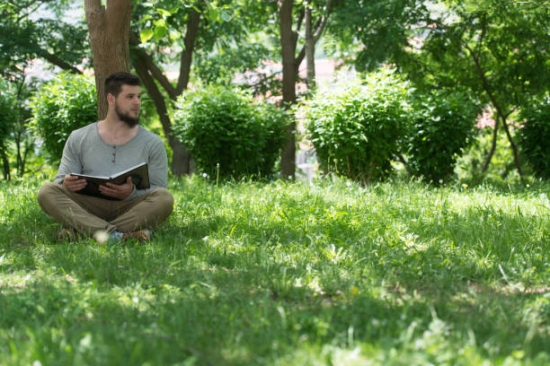 istock Young Muslim Guy Reading The Koran In Park 1334550548