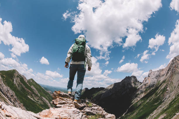 istock Successful woman backpacker hiking on alpine mountain peak 1334563866
