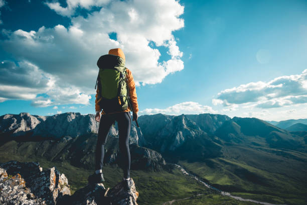istock Successful woman backpacker hiking on sunset alpine mountain peak 1334564598