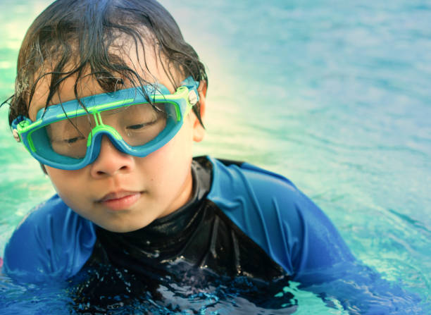 istock young boy in goggles in swimming pool 1334565323