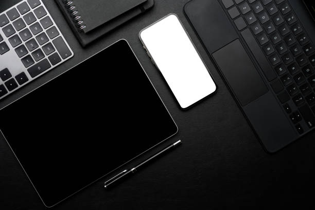 istock black workspace with black screen tablet, white screen smartphone mockup, keyboard 1334572213