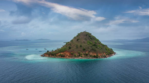 Kukusan Island Komodo National Park Indonesia Pulau Kukusan Panorama Pulau Kukusan- Kukusan Island Drone Point of View Aerial Panorama. View towards the tiny Pulau Kukusan Island in the Flores Sea under blue summer skyscape. Majelis Taklim, Pulau Kukusan Komodo National Park, Flores Sea, Labuan Bajo, East Nusa Tenggara - Flores, Indonesia, Southeast-Asia. pulau komodo stock pictures, royalty-free photos & images