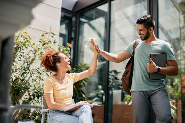 istock Young happy students giving high-five while greeting at the university. 1334589000