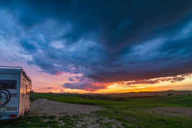 istock Sunset dramatic sky over camper van in Orcia Valley, Tuscany, Italy. Epic clouds above unique hill range landscape, alternative vanlife vacation concept. 1334589045