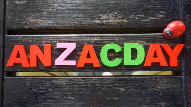 Colorful text of 'ANZACDAY' concept on wooden texture background