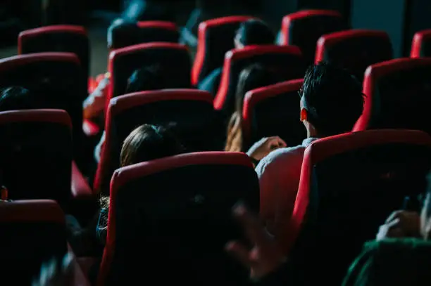 Photo of rear view asian chinese group of audience watching 3D movie in cinema enjoying the show with 3D glasses screaming excitement