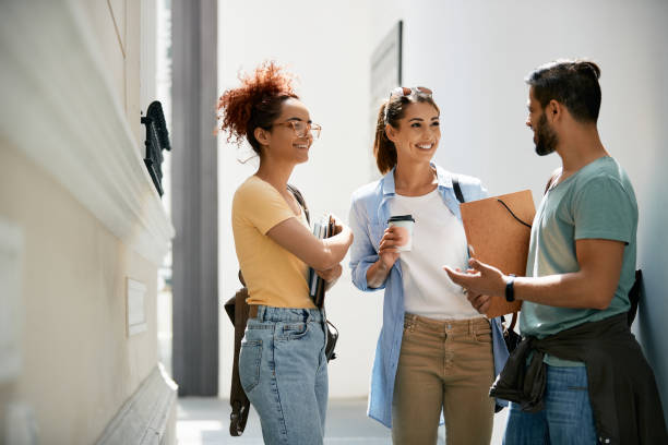 istock Happy university students talking to each other while standing in a hallway. 1334590663
