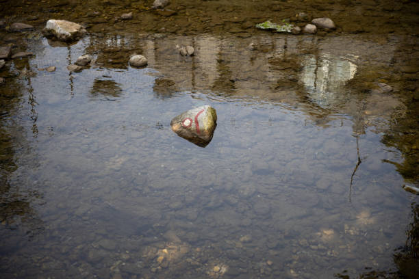 Trail blazing sign on a rock in a river Trail blazing sign on a rock in a river to be visible also when snow cover the land in Slovenian lower Alpine environment. trailblazing stock pictures, royalty-free photos & images