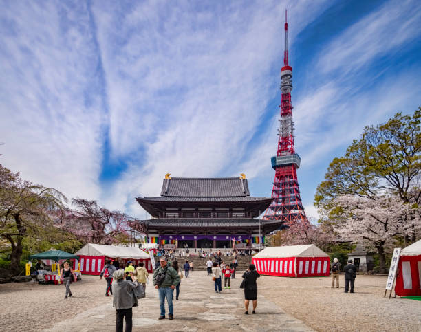 5 April 2019: Tokyo, Japan - Visitors at Zozoji Buddhist Temple in cherry blossom season, with the Tokyo Tower.