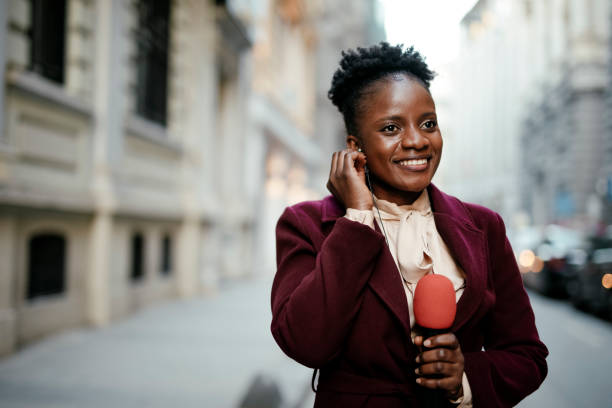 African female news reporter in live broadcasting. Young African journalist using a microphone at the city. African female news reporter in live broadcasting. journalist stock pictures, royalty-free photos & images