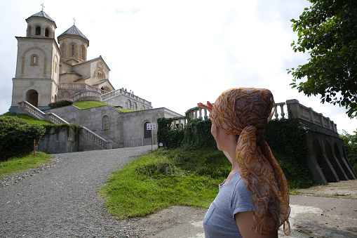 A woman looks at the Orthodox Church of the Holy Trinity on Mount Sameba. Sights of Adjara, Georgia.