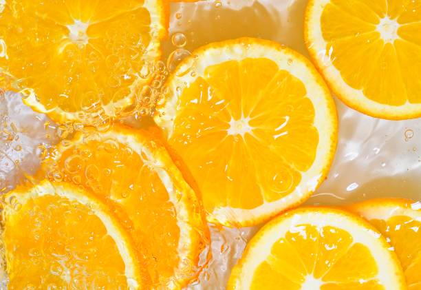 Slices of oranges in water on white background. Oranges close-up in liquid with bubbles. Slices of juicy ripe oranges in water. Macro image of fruits in water stock photo