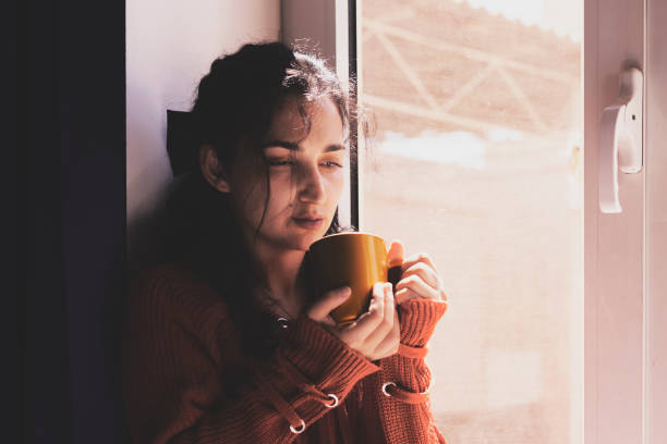 istock Cold autumn days - young multi-racial female drinks coffee in a cozy windowsill 1334606588