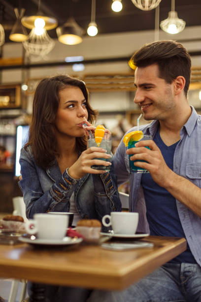 istock Couple smiling at each other while sipping cocktails during their date 1334609007