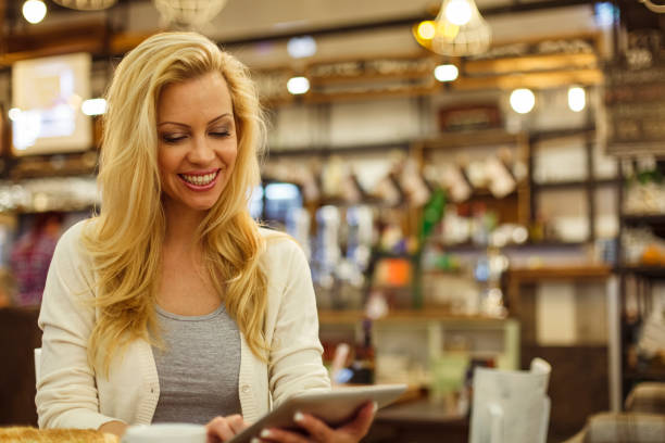 istock Smiling woman using digital tablet at the coffee shop 1334609548