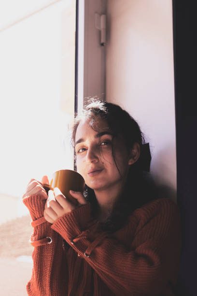 istock Cold autumn days - young multi-racial female drinks coffee in a cozy windowsill 1334609777