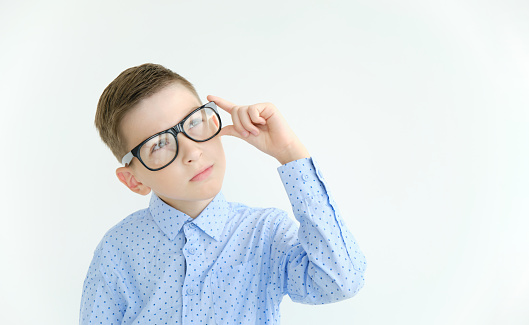 Pensive boy in glasses and a shirt on a white background. Place for your text.