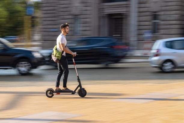 giovane studente aggira traffico con scooter elettrico - driving car traffic men foto e immagini stock