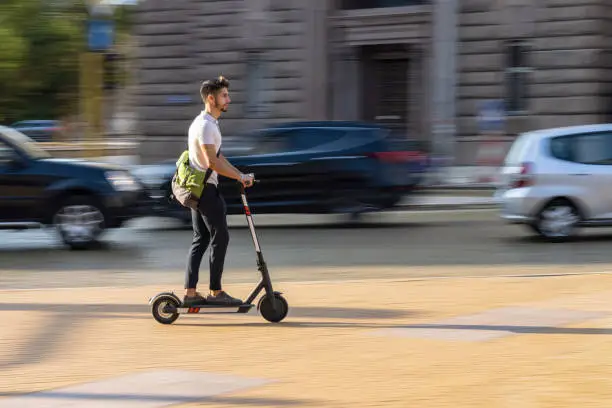 Motion blurred image of man riding electric scooter in the city