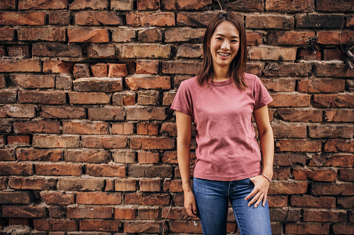 One woman, portrait of a beautiful Japanese woman standing by a brick wall outdoors.