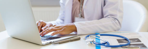 Panoramic banner with female doctor in white uniform working on laptop computer in hospital stock photo